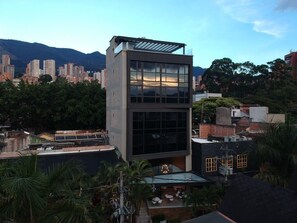 A modern building with large windows, a flat roof, and a view of surrounding high-rise buildings and mountains. - Epic Boutique Hotel (Medellín)