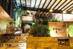 A hotel entrance with a staircase, a sign indicating 'HOTEL epic 1,' and a wooden planter with greenery. - Epic Boutique Hotel (Medellín)