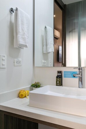 A modern bathroom with a large mirror, white sink, and towel rack. - Epic Boutique Hotel (Medellín)
