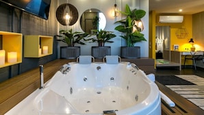 A modern bathroom with a large bathtub, multiple plants, and a mirror.