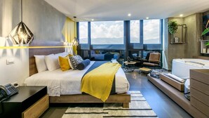 Une chambre d’hôtel moderne dotée d’un grand lit, d’un bureau, d’un coin salon et offrant une vue sur les montagnes.