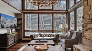A spacious living room with a large window, a wooden coffee table, a leather sofa, and a stone accent wall. - Stonebridge  (Park City)