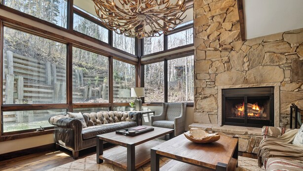 A spacious living room with a stone fireplace, large windows, and a leather sofa. - Stonebridge  (Park City)