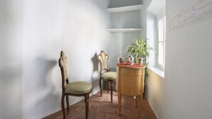 Une pièce d’angle avec deux chaises, une petite table sur laquelle est posée une plante, et une fenêtre.