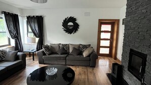 Un salon moderne avec un canapé, une table basse, une cheminée et un mur d’accent en pierre.