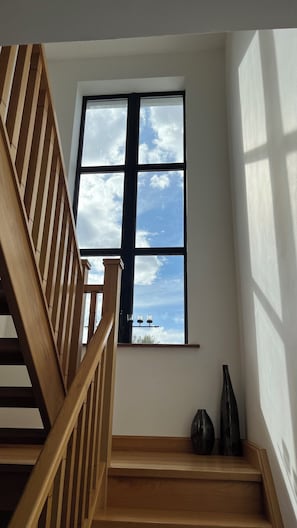 A wooden staircase leading to a room with a large window.
