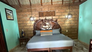 A bedroom with a brick wall, a wooden bed frame, and a ceiling with wooden beams. - Charming 2-bedroom apartment  in COL Majahua, Troncones, Mexico GRO. (COL Majahua)