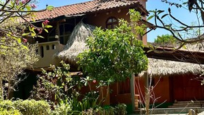 A traditional building with a thatched roof, surrounded by a garden with various plants and rocks. - Charming 2-bedroom apartment  in COL Majahua, Troncones, Mexico GRO. (COL Majahua)