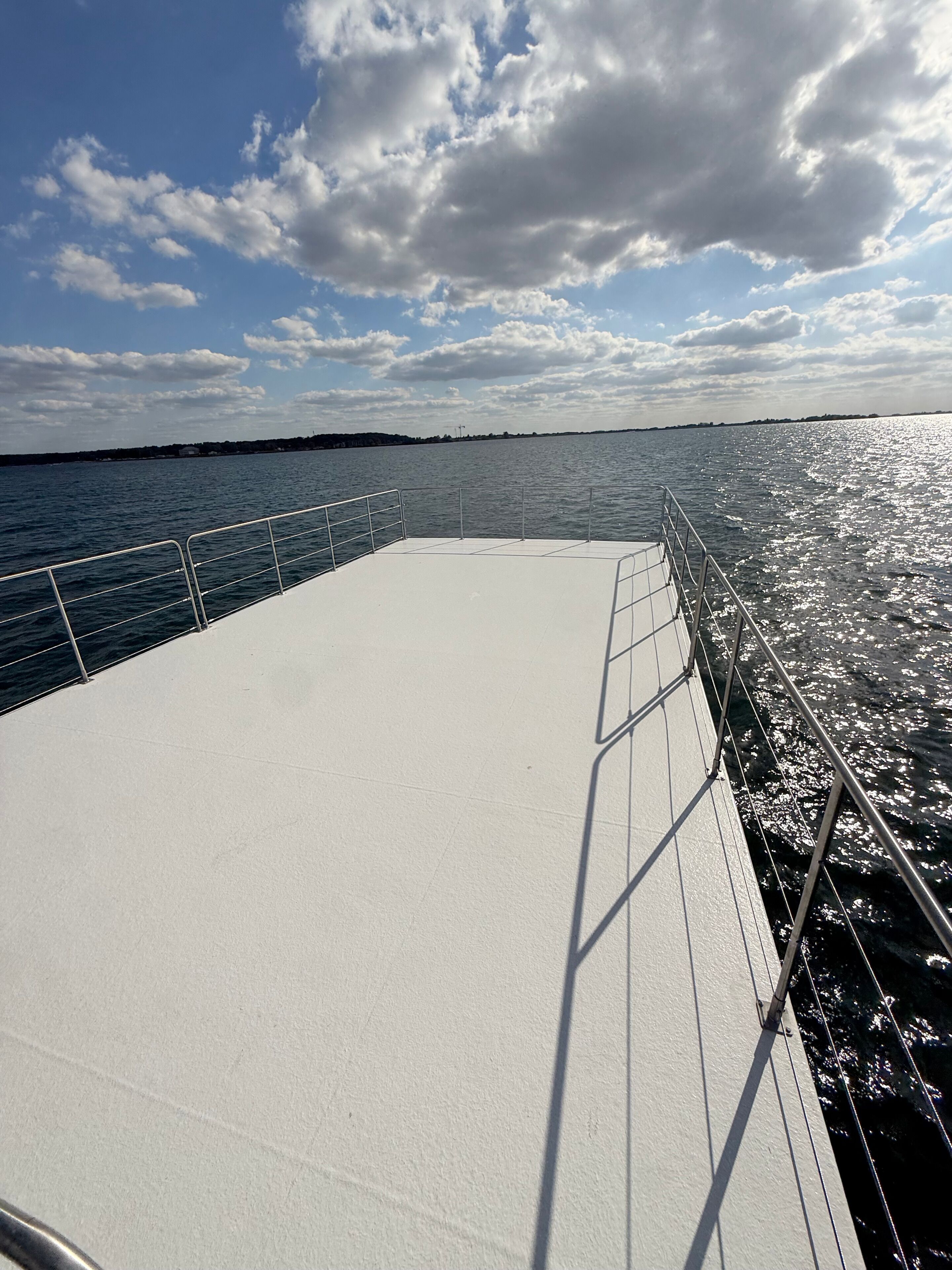 Cubierta de barco con barandillas metálicas y vista al agua y al cielo.