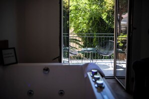 A room with a pool table, a glass door leading to an outdoor area with chairs and greenery.
