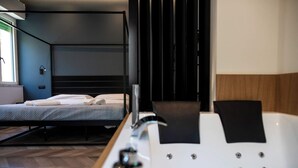 Una habitación de hotel moderna con cama, una bañera grande y ventana.