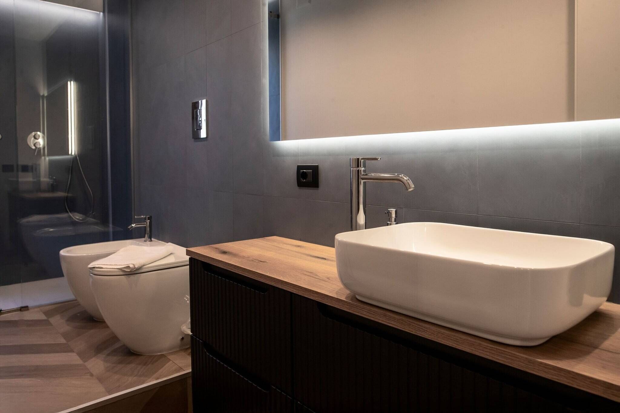 Un baño moderno con un lavamanos grande y rectangular, un inodoro separado y una cabina de ducha con paredes de cristal.