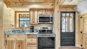 Een keuken met houten kastjes, een roestvrijstalen oven, een magnetron en een spoelbak.