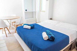 A hotel room with a bed, a desk, chairs, and a wardrobe.