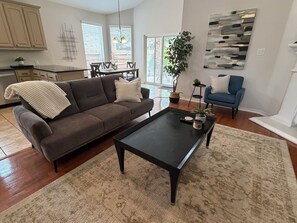 Ein Wohnzimmer mit einer Couch, einem Couchtisch und einem Essbereich mit Tisch und Stühlen.