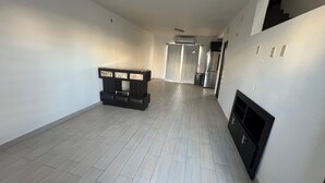 A spacious hallway with a modern fireplace, a built-in seating area, and a kitchen area visible in the background. - Casa Madeira (Mexicali)