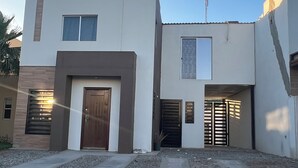 A modern two-story house with a central entrance, a small porch, and a garage. - Casa Madeira (Mexicali)