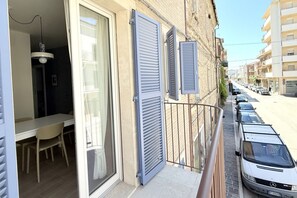 Un balcon avec un coin repas, une table blanche et une chaise.