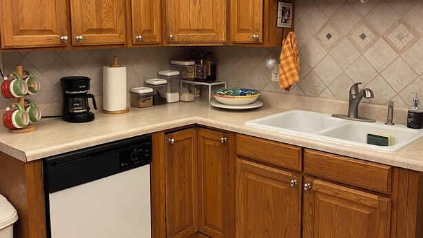 A kitchen with wooden cabinets, a dishwasher, a coffee maker, and a sink.
