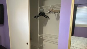 A room with a walk-in closet, a bed, and a mirror.