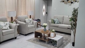 Ein Wohnzimmer mit zwei Sofas, einem Couchtisch, einem Deckenventilator und einem Wandkunstwerk.