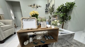 Ein Wohnzimmer mit einem Marmortisch, einer Couch, einem dekorativen Schild und einer Topfpflanze.