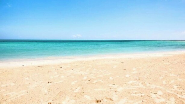 Ein Strand mit klarem türkisblauem Wasser und einem Sandufer.