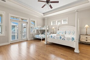 A bedroom with a bunk bed, a single bed, a ceiling fan, and a nightstand with a lamp. - Serenity by the Sea! 4BR Retreat, Sleeps 12, Walk to Beach (Panama City Beach)