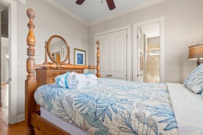 Ein Schlafzimmer mit einem hölzernen Himmelbett, einem Nachttisch, einem Spiegel und einer Tür zu einem anderen Raum.