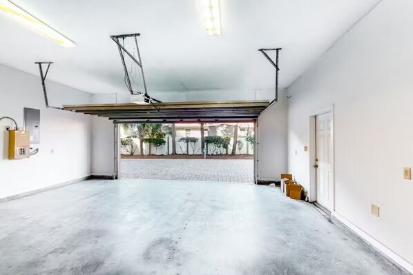 Eine geräumige Garage mit Betonboden, einer Garagentür und einer Metall-Deckenkonstruktion.