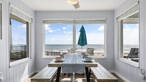 Comedor con una mesa preparada para cuatro personas, con vista a la playa.