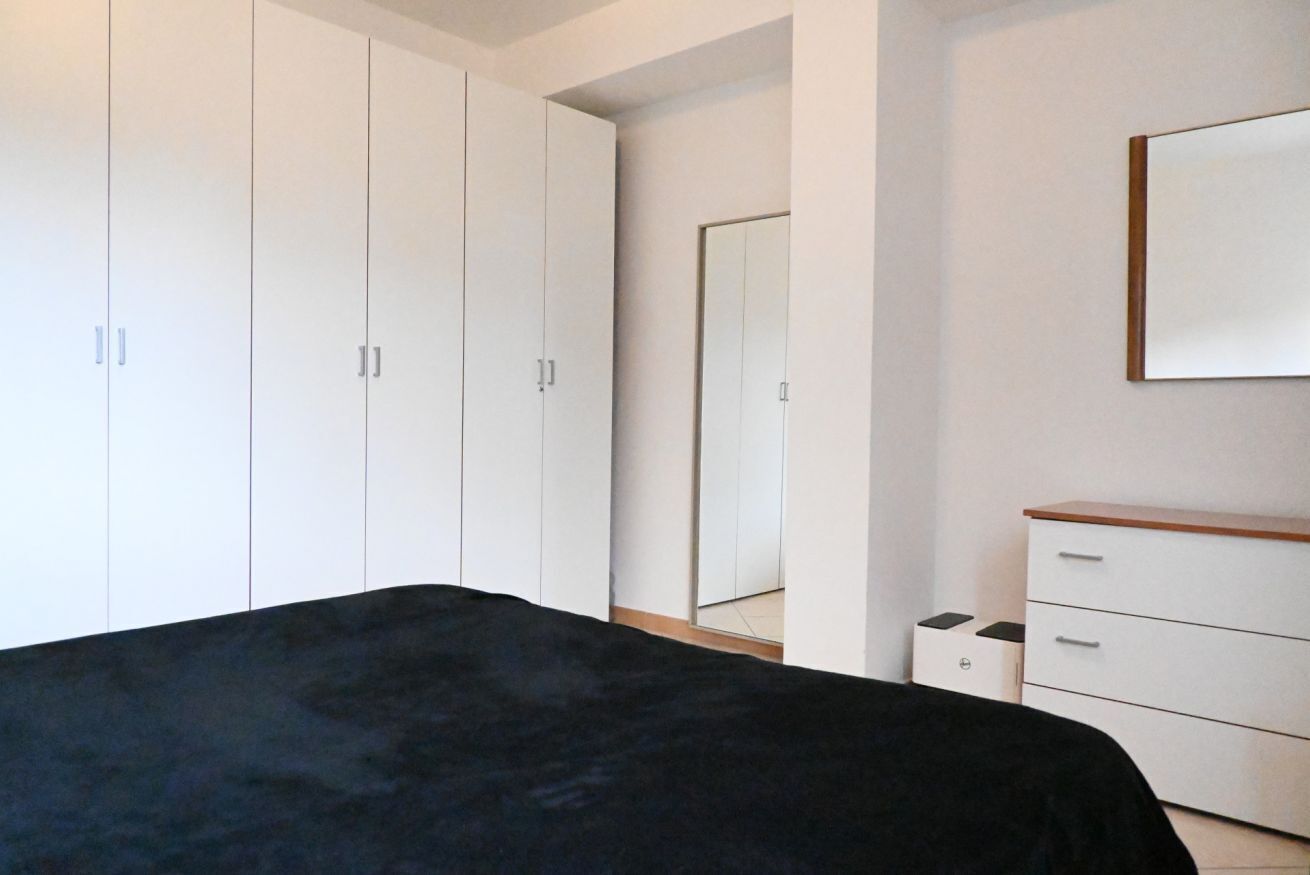 A bedroom with a bed, a dresser, a mirror, and a wardrobe.