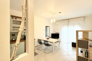 A modern kitchen with a dining area, a TV, and a staircase.