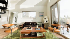 A modern living room with a sofa, two armchairs, a coffee table, and a large window. - Modern Alpine Cabin in Twin Lakes (Twin Lakes)