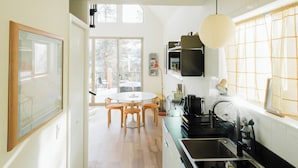 A modern kitchen with a large island, wooden flooring, and a view to a dining area. - Modern Alpine Cabin in Twin Lakes (Twin Lakes)