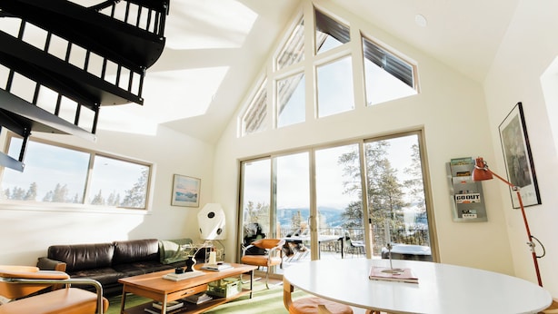 A spacious living area with a large window, a staircase, a dining table, and a sofa. - Modern Alpine Cabin in Twin Lakes (Twin Lakes)