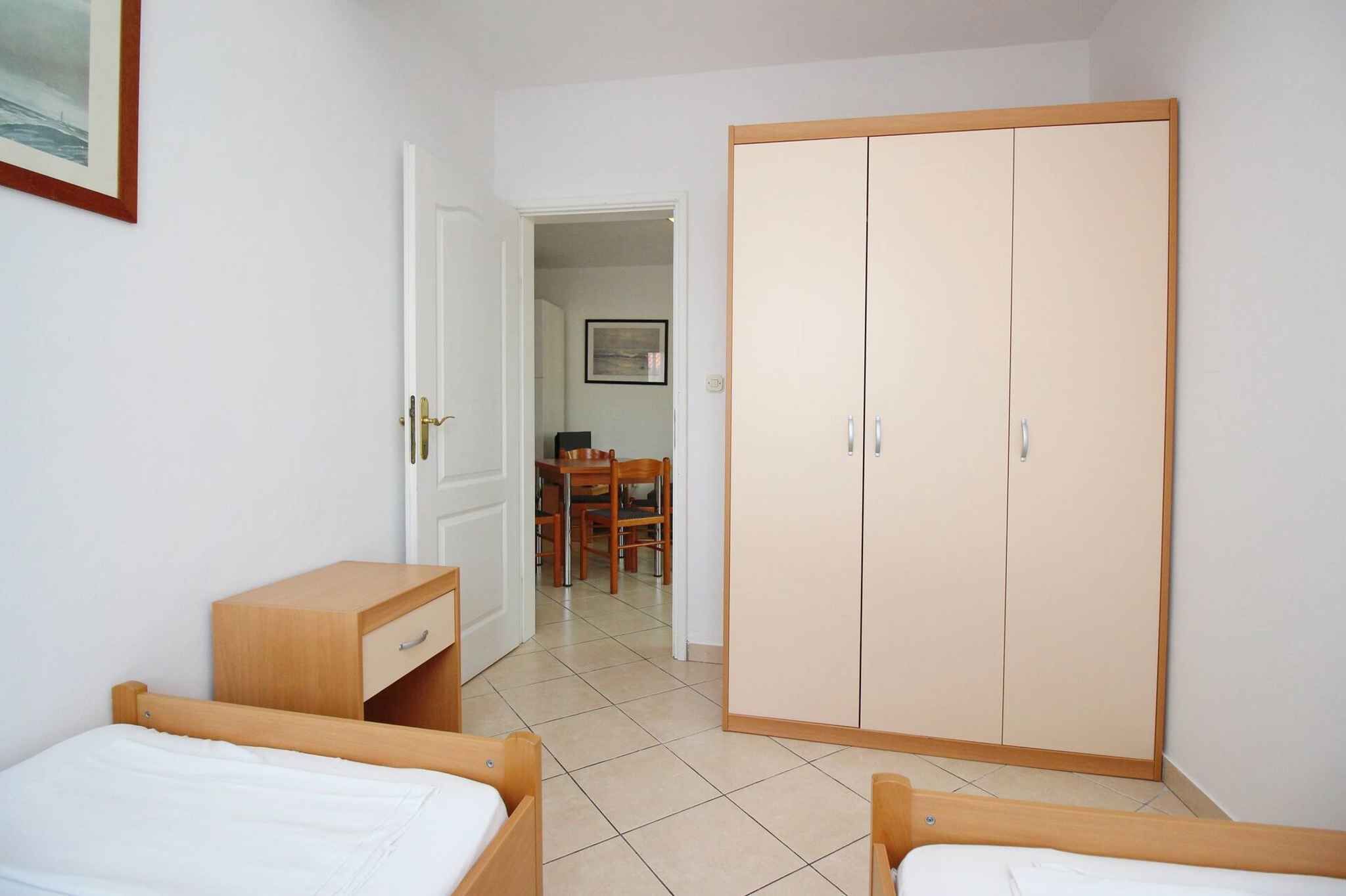 Une chambre à coucher avec deux lits en bois, une armoire, un bureau et une chaise.