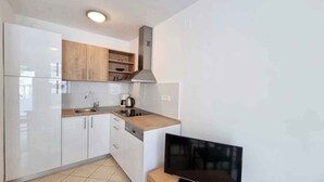 Eine moderne Küche mit weißen Schränken, einer Edelstahl-Spüle und einem eingebauten Backofen.