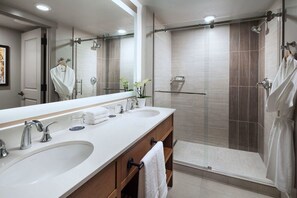 Features a dual sink vanity, large mirror, and walk-in shower with glass door.
