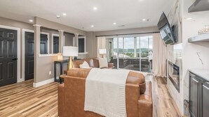 Un dormitorio moderno con una cama grande, televisor y balcón con vistas.