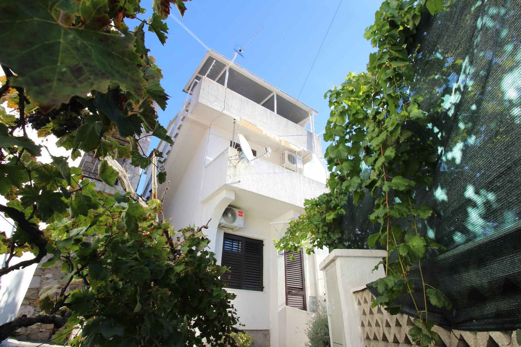 A two-story building with a balcony, surrounded by greenery.