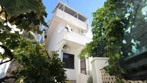 Un immeuble de deux étages doté d’un balcon, entouré de verdure.