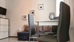 Un salon moderne comprenant un canapé, deux fauteuils, un téléviseur et une petite table agrémentée d’objets décoratifs.