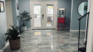 Un pasillo con suelo de mármol, una planta en maceta, una máquina expendedora roja y una bicicleta.