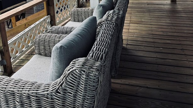 Un espacio de estar techado al aire libre con muebles de mimbre y vistas del exterior.