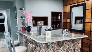 Una cocina con una isla de piedra, taburetes de bar y estantes con objetos decorativos.