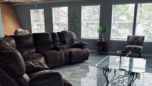 Una sala de estar moderna con un sofá modular, una mesa de centro de vidrio y amplios ventanales con vistas al exterior.