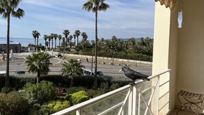 A balcony with a view of palm trees and a parking lot.