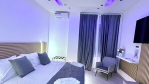Habitación de hotel moderna con una cama grande, una silla, un televisor y un equipo de aire acondicionado.