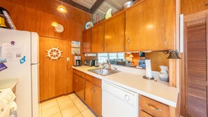 Une cuisine avec des meubles de rangement en bois, un lave-vaisselle, un évier et une cuisinière.